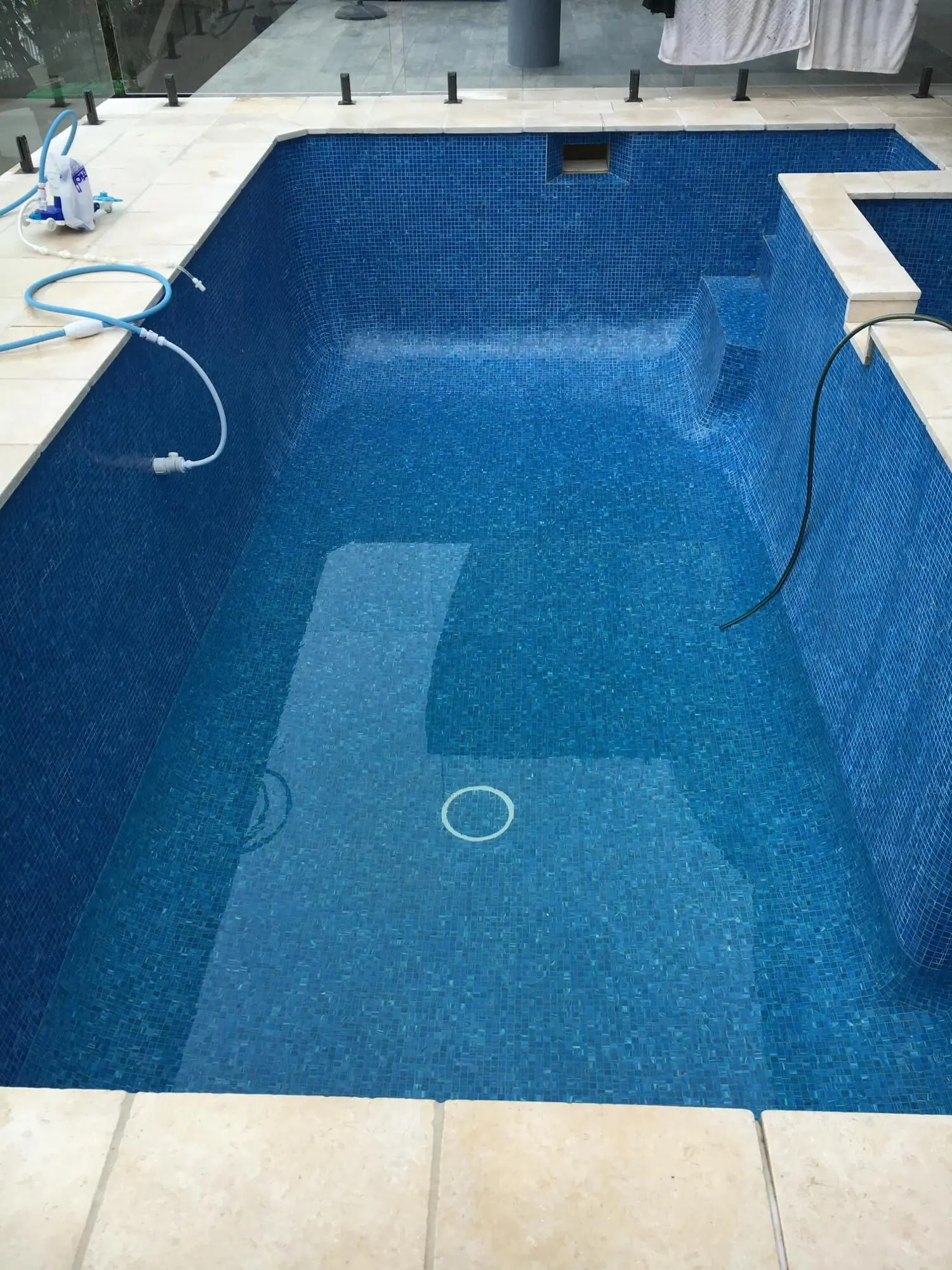 Renovated pool with a fully tiled blue mosaic interior and stone coping