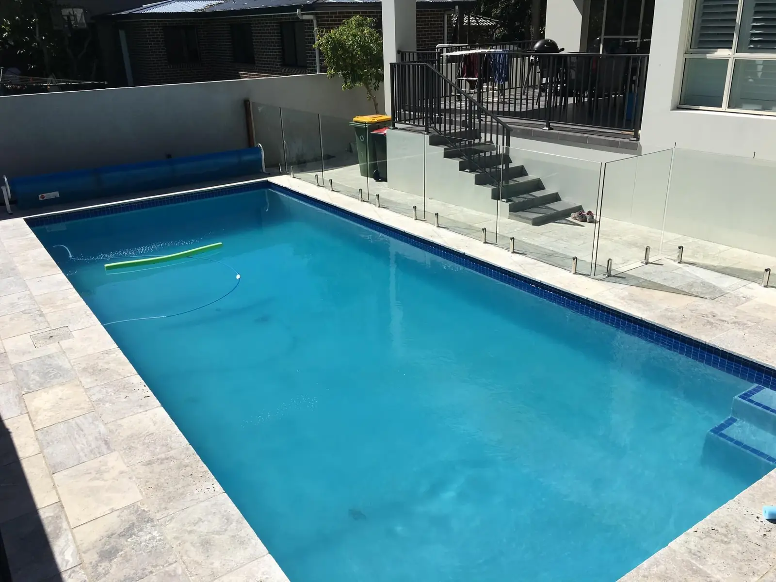 Renovated pool with travertine paving and frameless glass fence