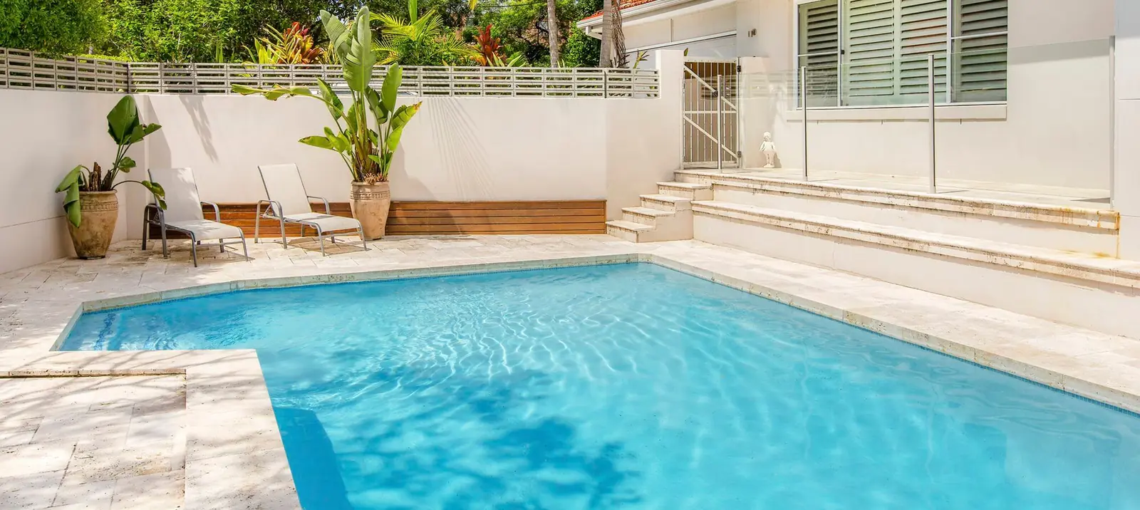 Renovated West Pennant Hills pool with travertine paving, timber bench and garden feature wall